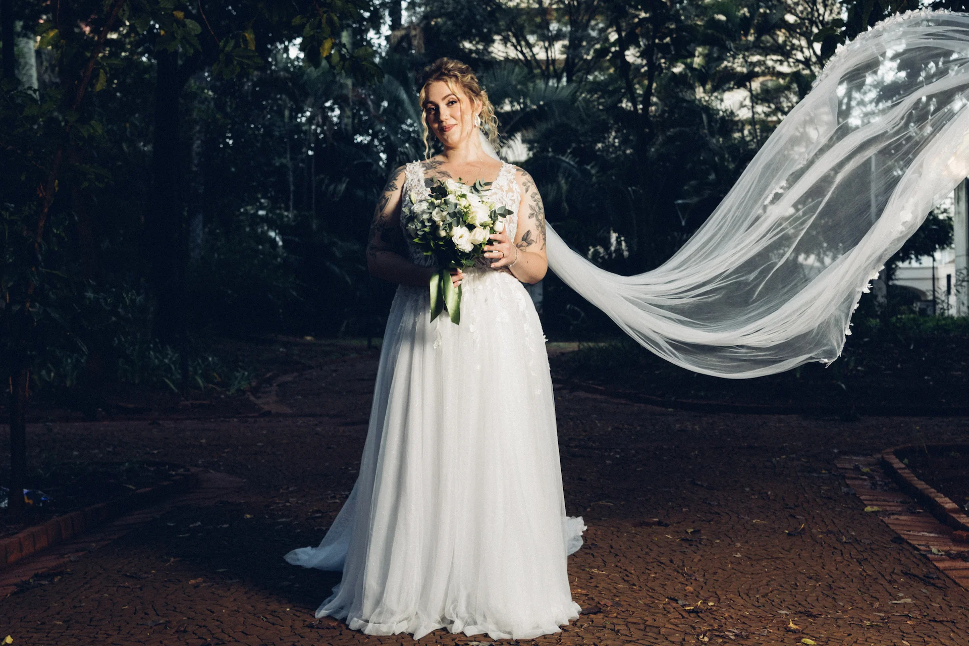 Noiva em praça com vestido de casamento e buquê de flores